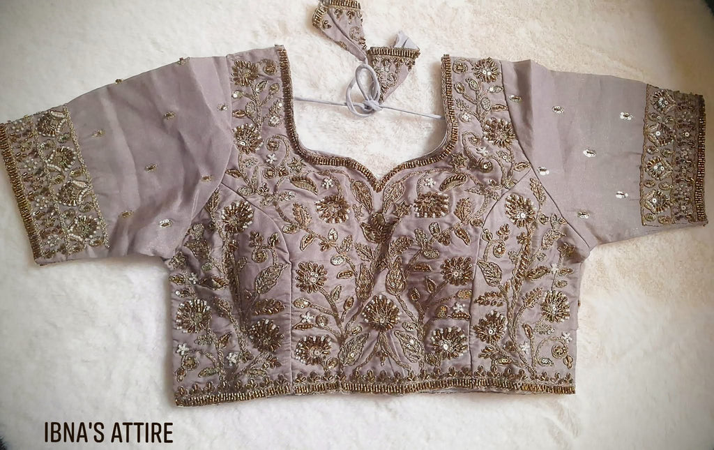 Flat lay and close-up view of a taupe/grey soft silk blouse with intricate copper beadwork, sequin floral motifs, sweetheart neckline, padded construction, and back latkans.Tubelight bugle beads lining the neckline, waist, and cuffs.  Intertwining vine and bloom patterns filled with shimmering sequins and pearl seeds. 