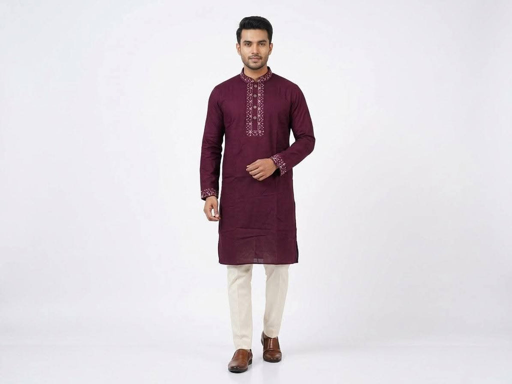 Full-length front view of a male model wearing a plum maroon cotton panjabi with embroidered collar and cuffs, paired with cream trousers and brown leather shoes.Subtle embroidery along the band collar and cuffs that adds a touch of sparkle without overpowering the classic look.  