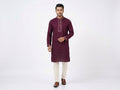 Full-length front view of a male model wearing a plum maroon cotton panjabi with embroidered collar and cuffs, paired with cream trousers and brown leather shoes.Subtle embroidery along the band collar and cuffs that adds a touch of sparkle without overpowering the classic look.  