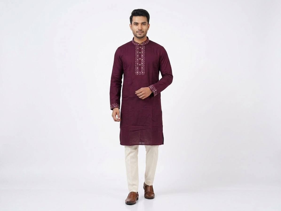 Full-length front view of a male model wearing a plum maroon cotton panjabi with embroidered collar and cuffs, paired with cream trousers and brown leather shoes.Subtle embroidery along the band collar and cuffs that adds a touch of sparkle without overpowering the classic look.  