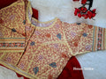 Beige multi color malai cotton blouse displayed flat over a deep red fabric on a soft white fur surface, highlighting fine Kantha stitch embroidery and a front hook closure.