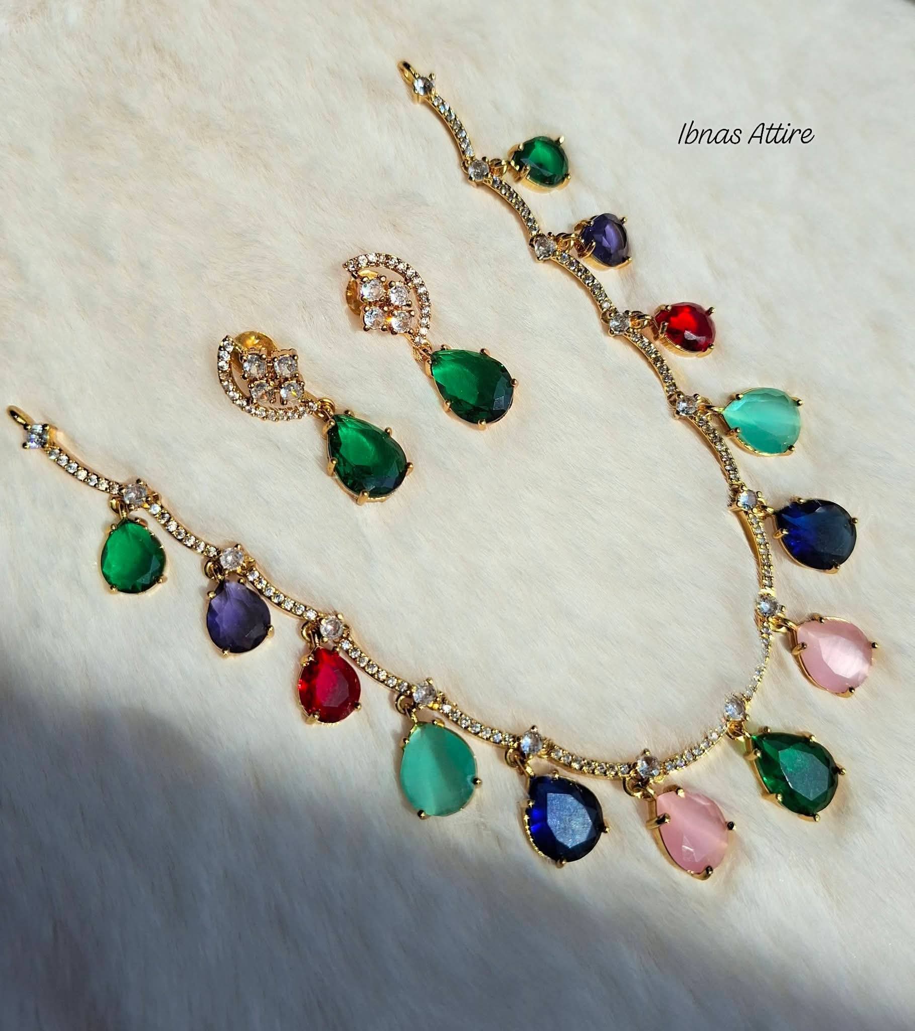 Gold-plated traditional jewelry set featuring a necklace, earrings. colorful teardrop-shaped gemstones in green, blue, pink, red, and purple