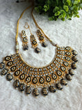 Featuring Kundan Choker Necklace Set with Maang Tikka & Earrings.  Deep black meenakari outlines framing the sparkling glass kundan stones for a dramatic look.Cascading lower border accents featuring hand-painted floral details over black beads.Includes a perfectly matching pair of earrings and a maang tikka to effortlessly complete your ethnic ensemble.