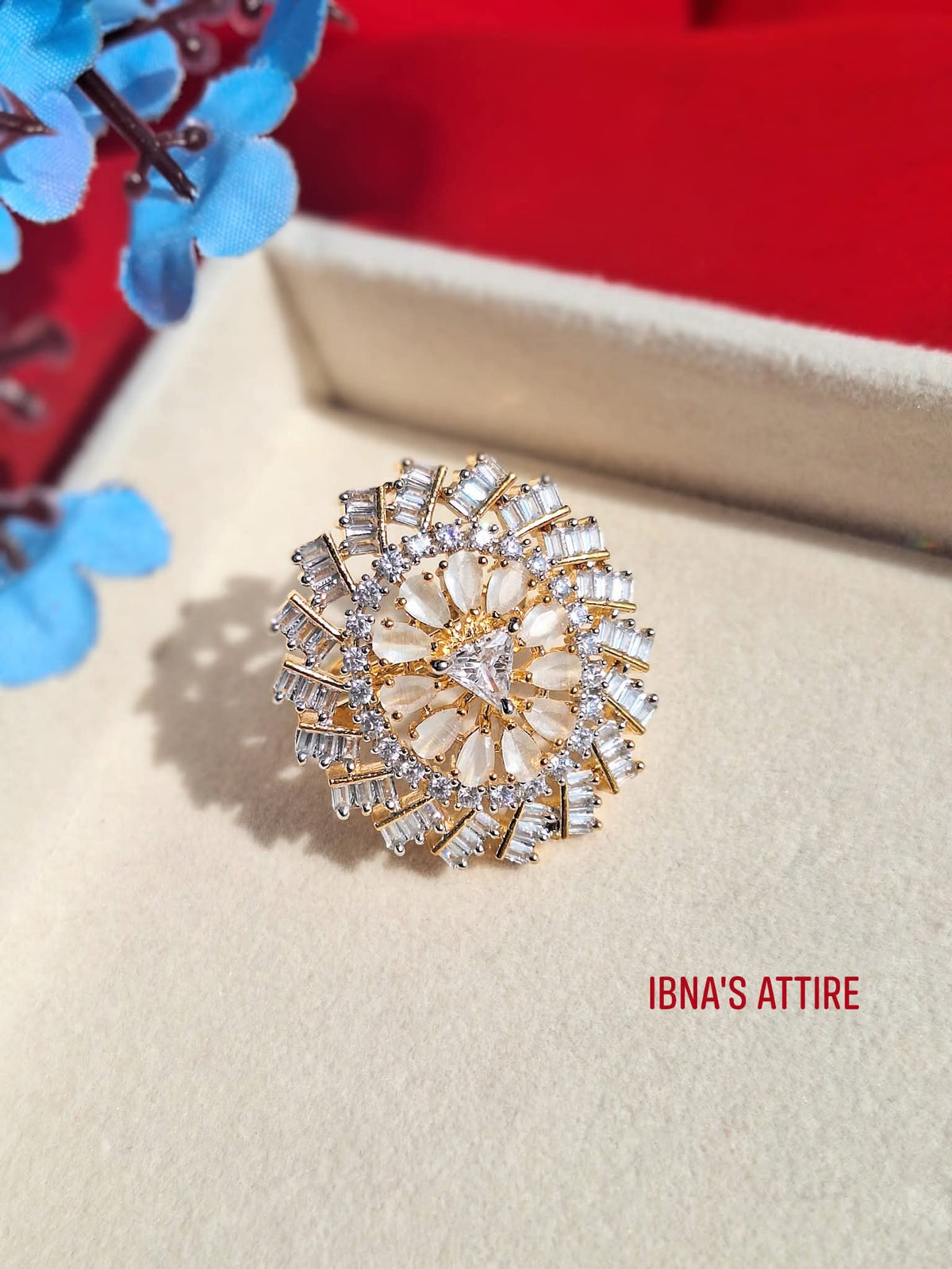 Featuring a Gold-Plated AD Adjustable Statement Ring in off white color. Delicate pear-shaped stone petals anchored by a striking triangular stone centerpiece.Radiating tiers of brilliant-cut baguette and round American Diamond stones creating maximum light reflection.