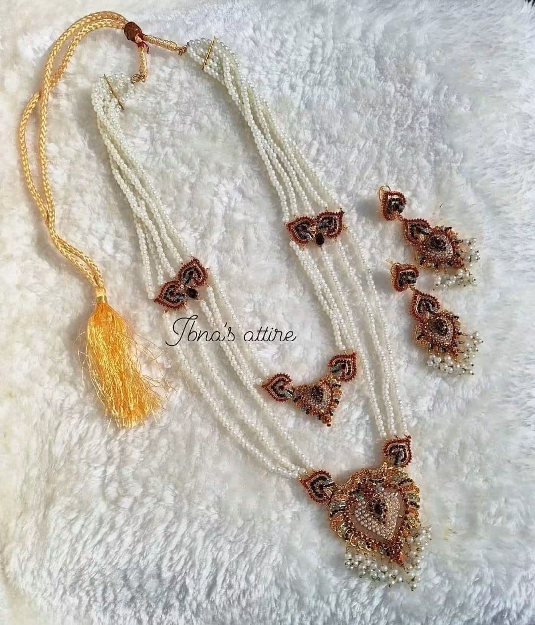Featuring Multi-Layered Sita Haar with Matching Jhumka/Drop Earrings -Intricately detailed centerpieces featuring traditional multi-color stone settings (combining red, blue, orange, and dark tones) within a golden filigree frame.