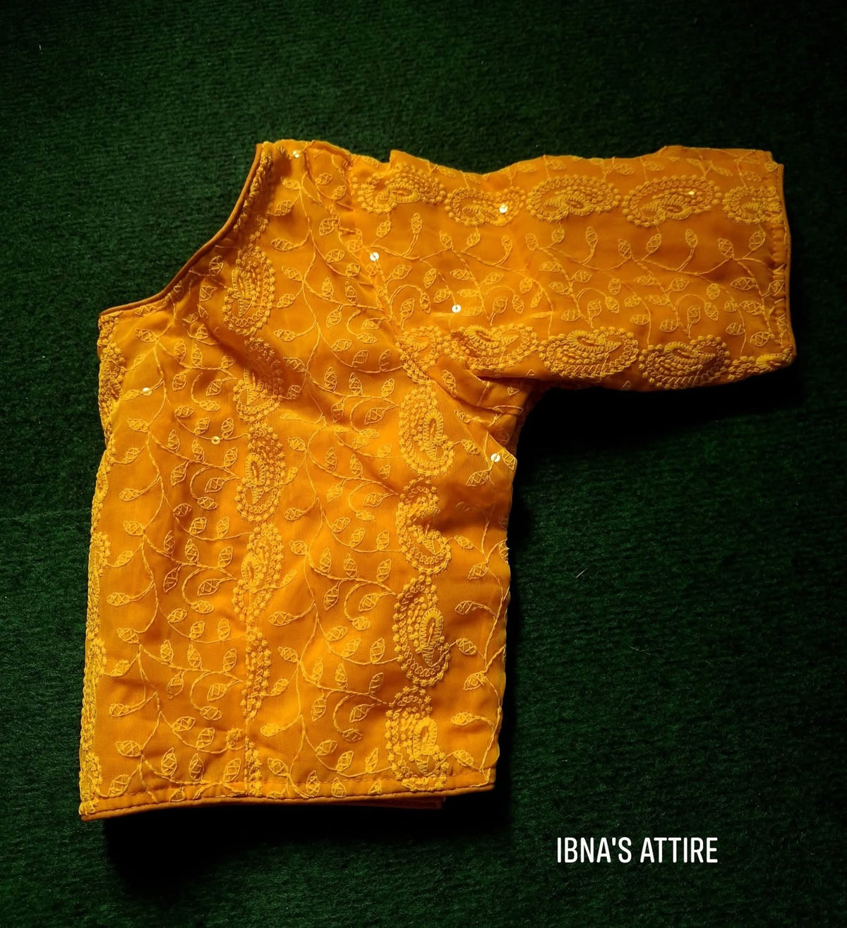 Soft Georgette Chikankari Blouse mustard yellow color lying on a greeny background
