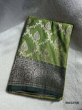 Mehendi green banarasi muga katan silk saree with silver patterns on a white fabric background