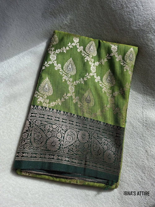 Mehendi green banarasi muga katan silk saree with silver patterns on a white fabric background