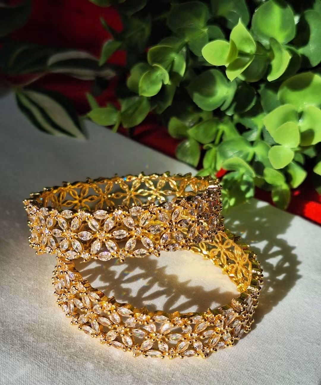 Featuring Gold Plated American Diamond (AD) Floral Bangles Pair (2 Pieces) , Petal-like marquise CZ stones intricately linked in repeating flower motifs.