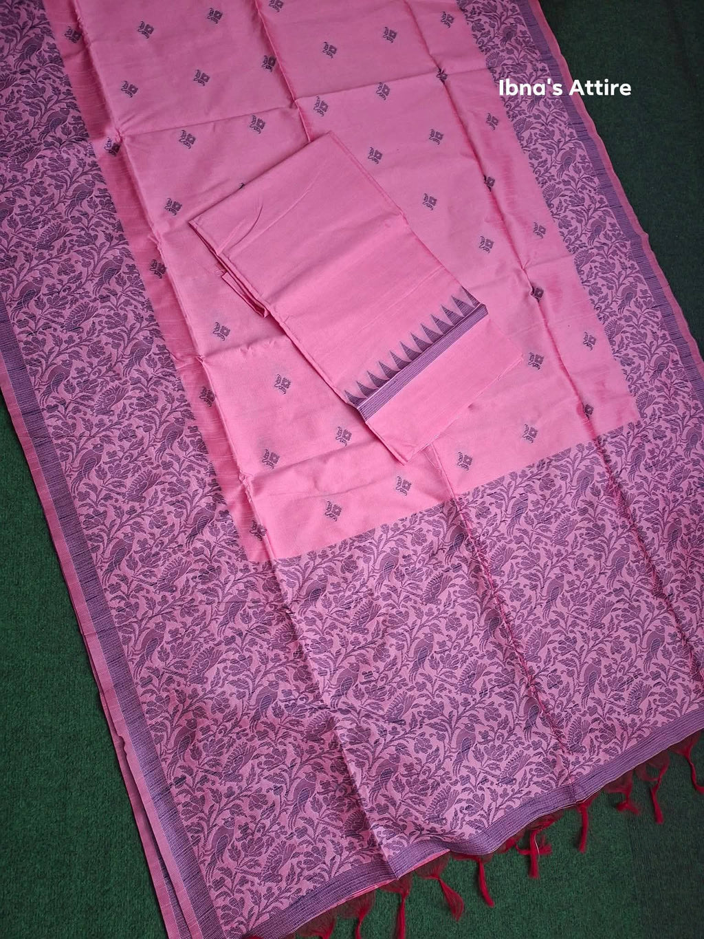 Pink madhibani gicha silk saree on a dark green textured surface. 