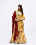 A woman modeling a traditional Indian outfit consisting of a yellow embroidered rayon kurta and flared skirt with a deep red dupatta, set against a plain white studio background.