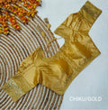Metallic chiku/gold Jasmin silk saree blouse displayed flat on a circular jute mat, featuring gold sequence embroidery on the neck, hem, and puff sleeve cuffs. Fine gold sequence and matching threadwork defining the round neck and bottom hemline. 