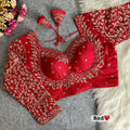 Crimson red pure Vichitra silk readymade blouse with heavy gold zari embroidery, full long sleeves, sweetheart Mumtaz neck, back open style, and fan latkans displayed on a grey felt background.  