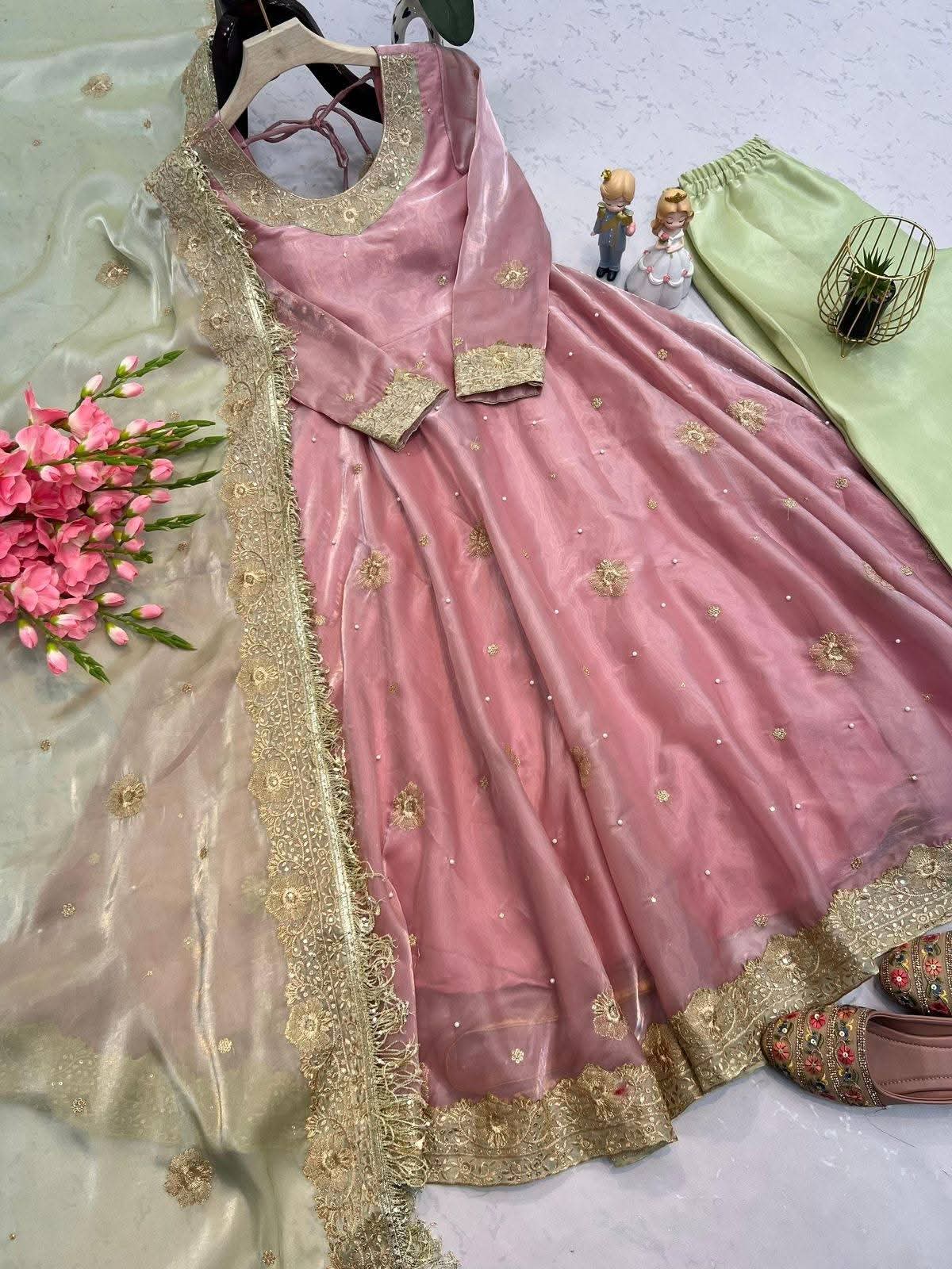 Pink traditional outfit with gold embroidery on a light gray background