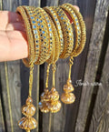 Gold bangles with dangling crystals held against a wooden background