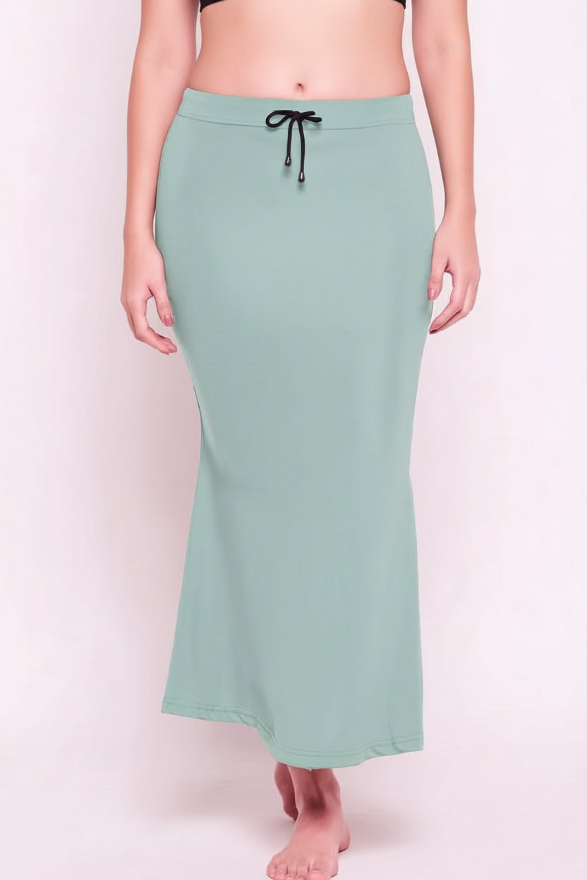 Mint green skirt worn by a person on a light pink background