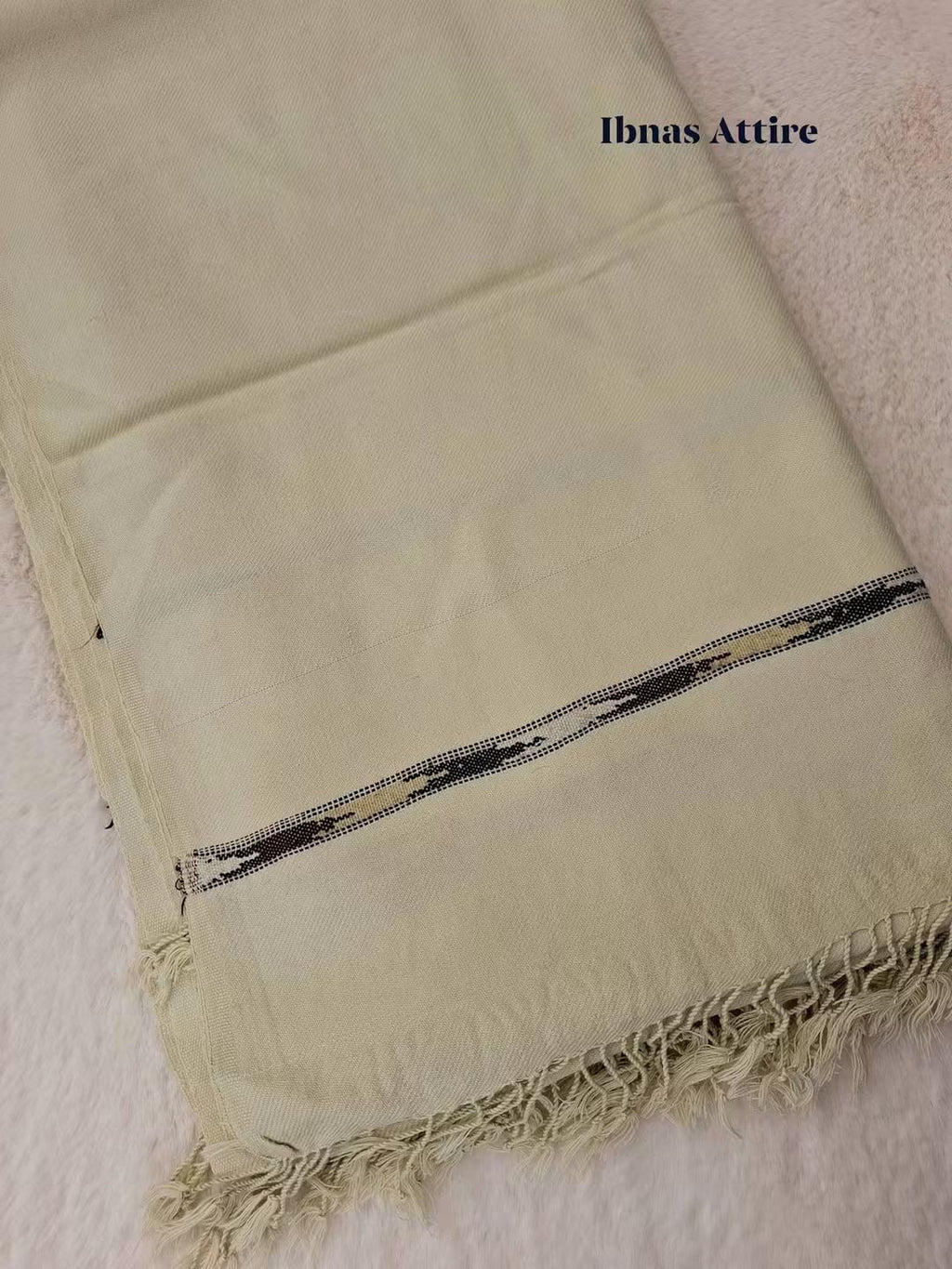 Folded off-white/beige Pashmina winter wool shawl showcasing a textured weave, detailed border stripe, and fringe tassels on a soft background.