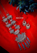 Long oxidized silver chain necklace with elephant links, crescent pendant, mirror charms, matching earrings, laid flat on a red fabric background with blue flowers.