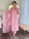 Model wearing a light pink chikan kari sequence-worked Roman silk long kurti and matching trousers, holding a floral digital-printed organza dupatta indoors.High-quality Roman silk offering a structured yet comfortable everyday or party fit.