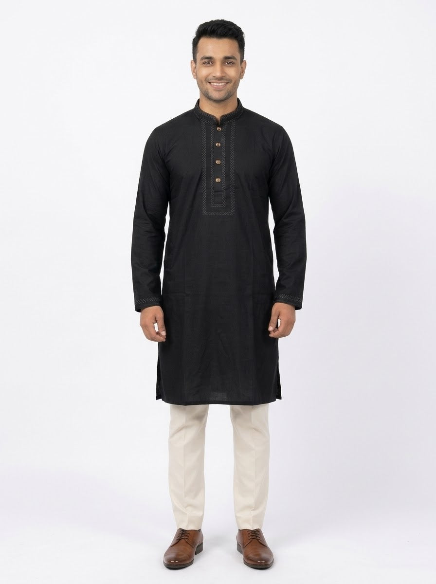 Full-length front view of a male model wearing a jet black micro stitch panjabi with embroidered collar and placket, paired with cream trousers and brown leather shoes.Tagged size 40 engineered with a relaxed silhouette to fit up to a 42-inch chest seamlessly.Dual-function button layout combining metallic charm on the outside with easy snap functionality.Durable, smooth-textured fabric designed for crease resistance and easy wearability.