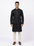 Full-length front view of a male model wearing a jet black micro stitch panjabi with embroidered collar and placket, paired with cream trousers and brown leather shoes.Tagged size 40 engineered with a relaxed silhouette to fit up to a 42-inch chest seamlessly.Dual-function button layout combining metallic charm on the outside with easy snap functionality.Durable, smooth-textured fabric designed for crease resistance and easy wearability.