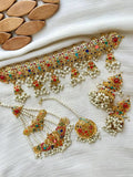 Gold finish Kundan choker, jhumkas, and maang tikka with pearl sahara strings, laid flat on a white fabric background near wooden props.